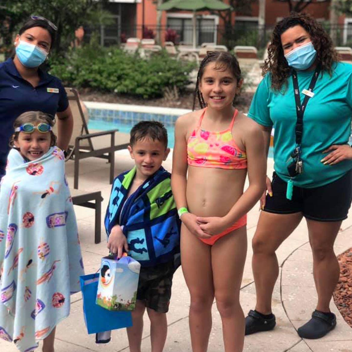 Featured Member, Sara Perez's family stands with two masked HICV Team Members outside of our River Island pool.
