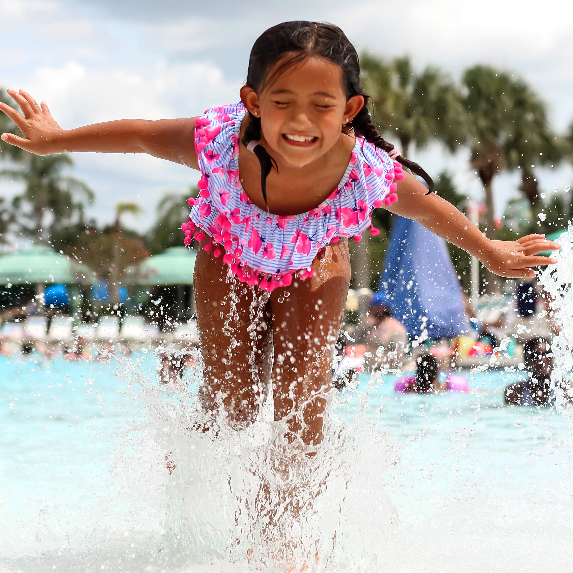 A girl wearing a pink, striped swimsuit splashed in the zero-entry pool at our Orange Lake Resort located in Orlando, Florida.