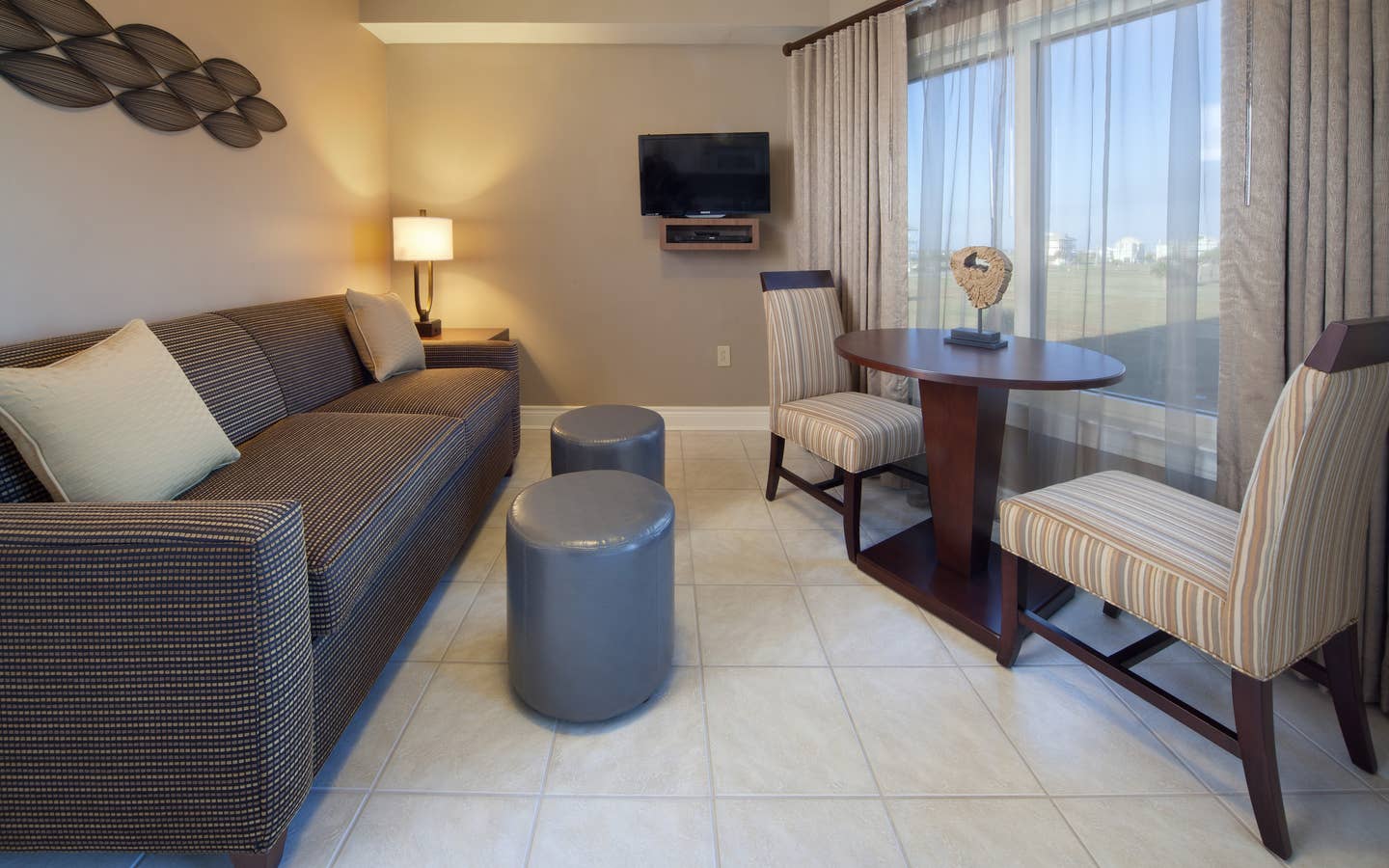 Living room with couch, flat screen TV, and large window with seating area in a villa at Galveston Beach Resort