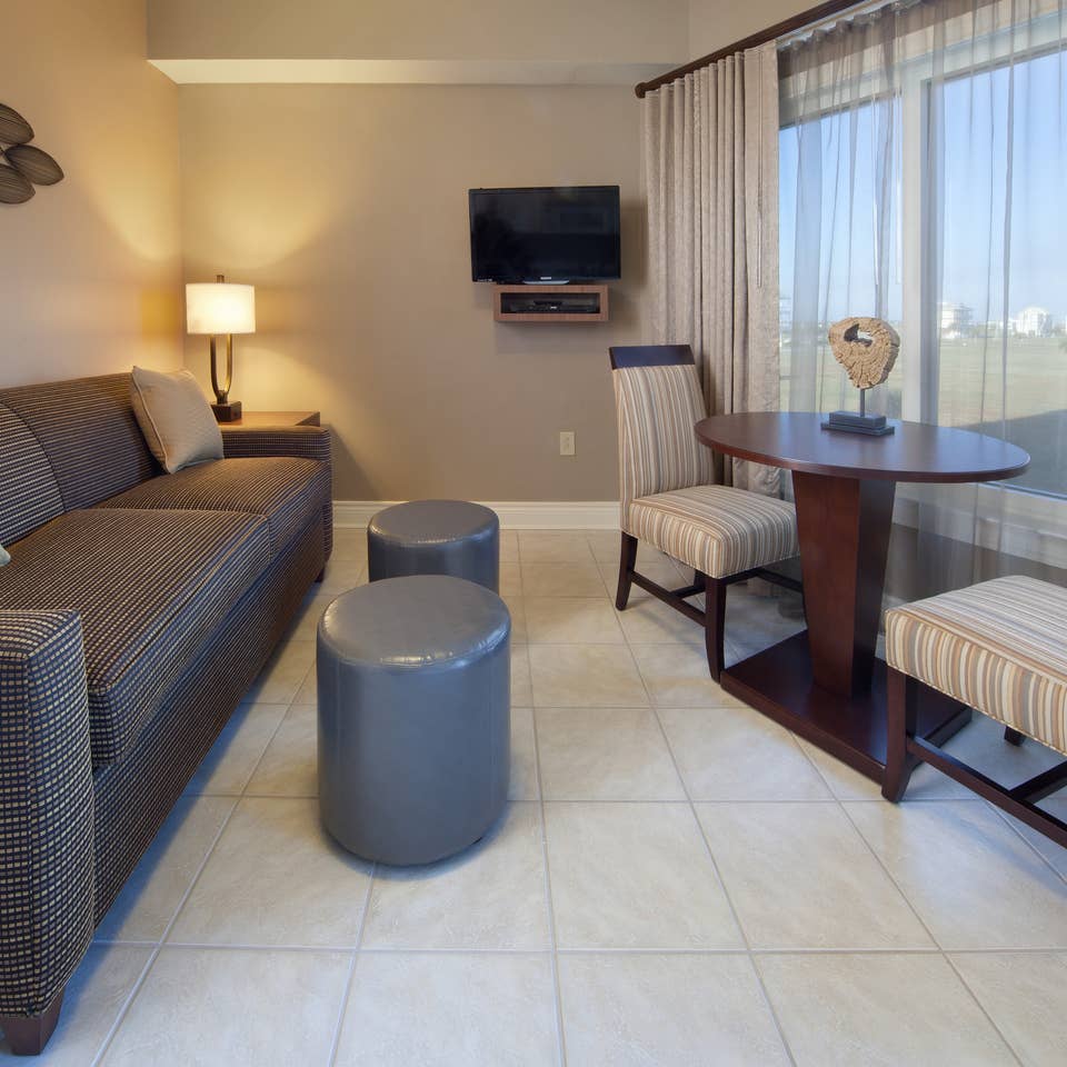 Living room with couch, flat screen TV, and large window with seating area in a villa at Galveston Beach Resort