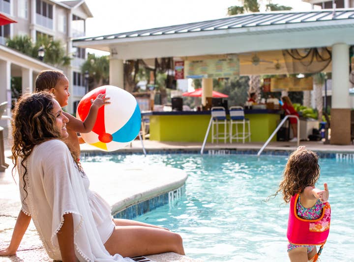 Mother with two children sitting on edge of outdoor pool at South Beach Resort in Myrtle Beach, South Carolina.