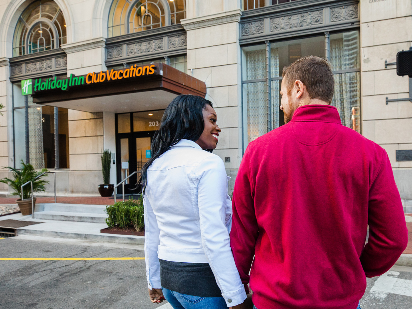 Sally Butan (left) of @butanclan and her husband cross the street towards our New Orleans resort with signage that reads, 'Holiday Inn Club Vacations.'