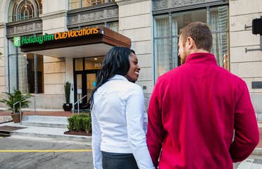 Sally Butan (left) of @butanclan and her husband cross the street towards our New Orleans resort with signage that reads, 'Holiday Inn Club Vacations.'