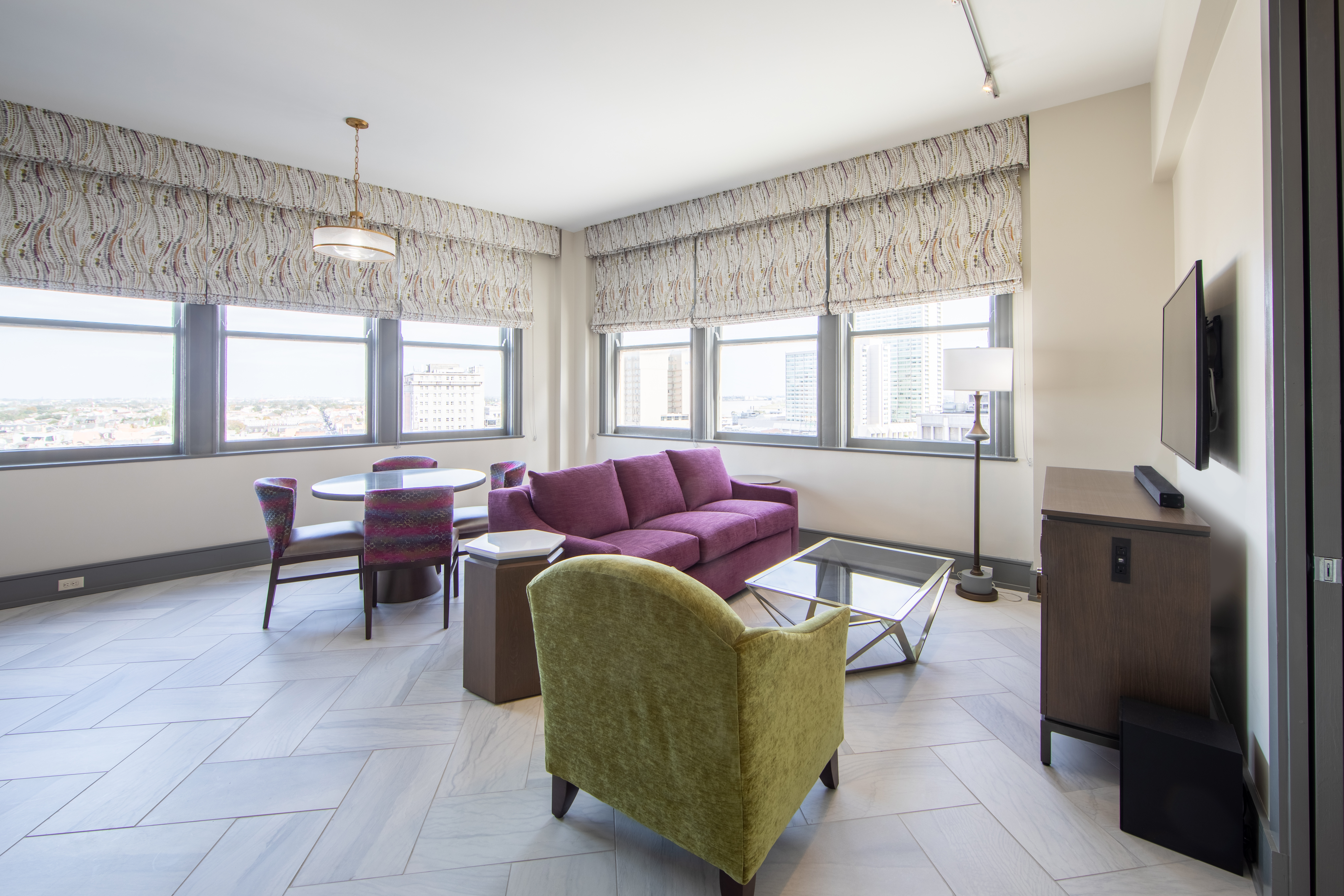 Living room with purple couch, lime green chair and flat screen TV surrounded by six windows at New Orleans Resort in Louisiana.
