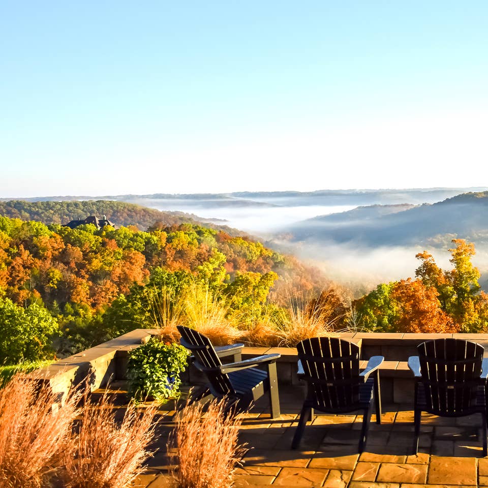 Several Adirondack chairs overlook fall foliage in Branson, MO.