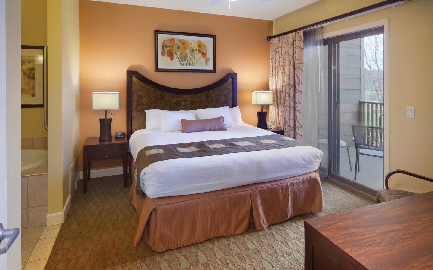 Master bedroom with attached bathroom and access to furnished balcony in a villa at Lake Geneva Resort