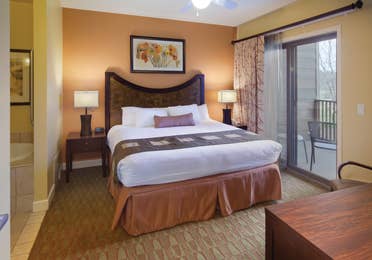 Master bedroom with attached bathroom and access to furnished balcony in a villa at Lake Geneva Resort