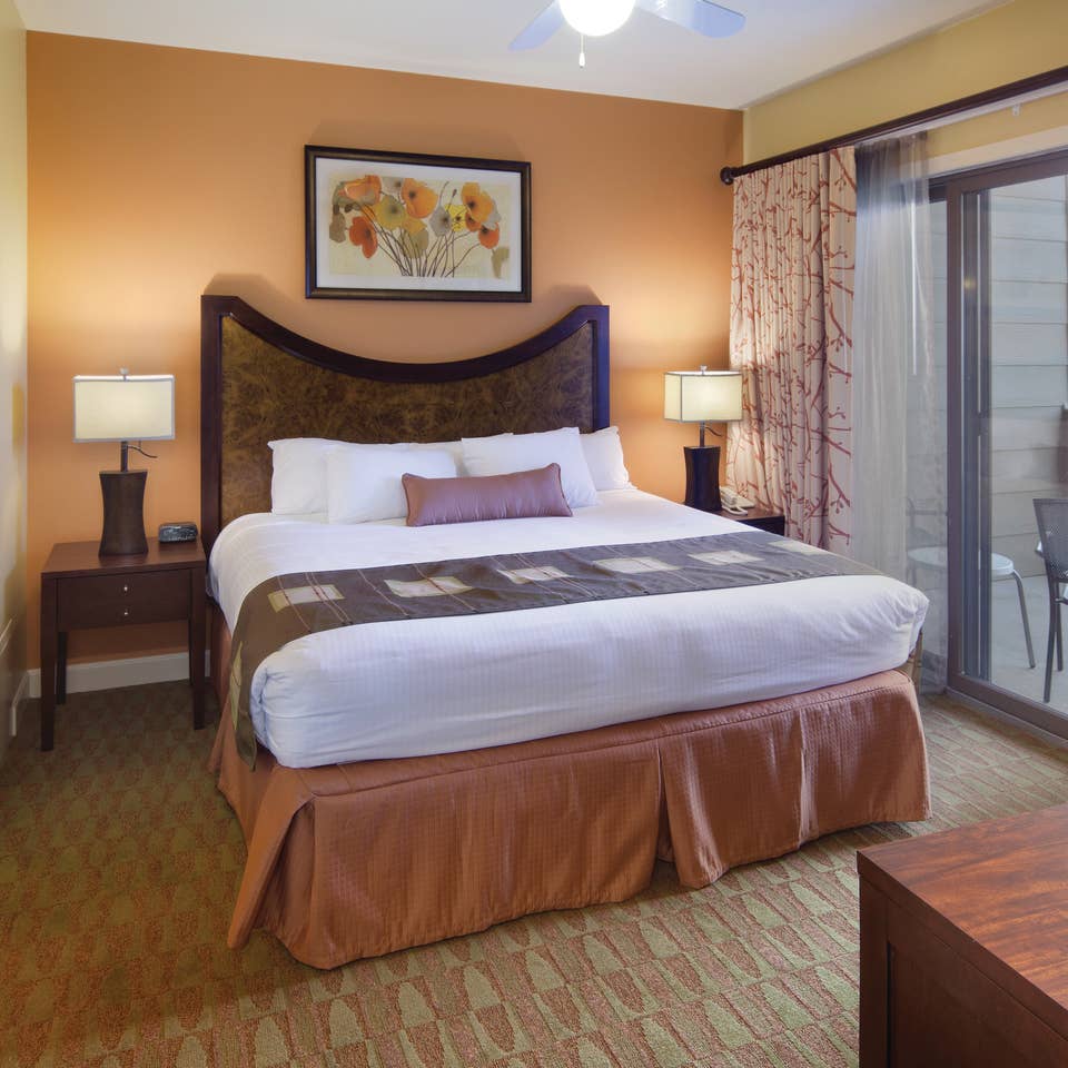 Master bedroom with attached bathroom and access to furnished balcony in a villa at Lake Geneva Resort