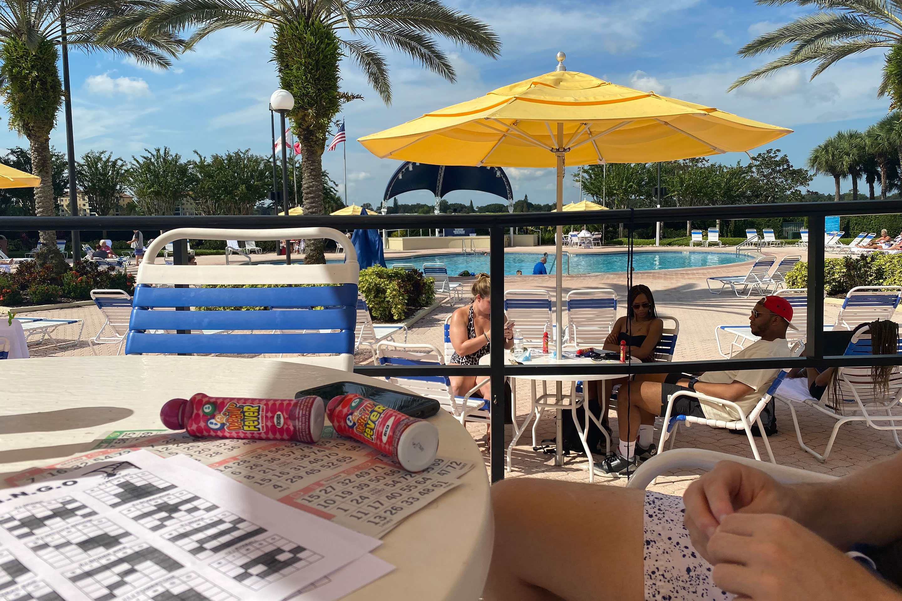 guests sit under a yellow umbrella playing bingo near the River Island pool at our Orange Lake resort in Orlando, Florida.