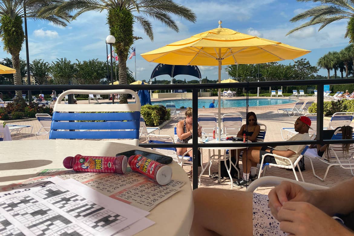 guests sit under a yellow umbrella playing bingo near the River Island pool at our Orange Lake resort in Orlando, Florida.