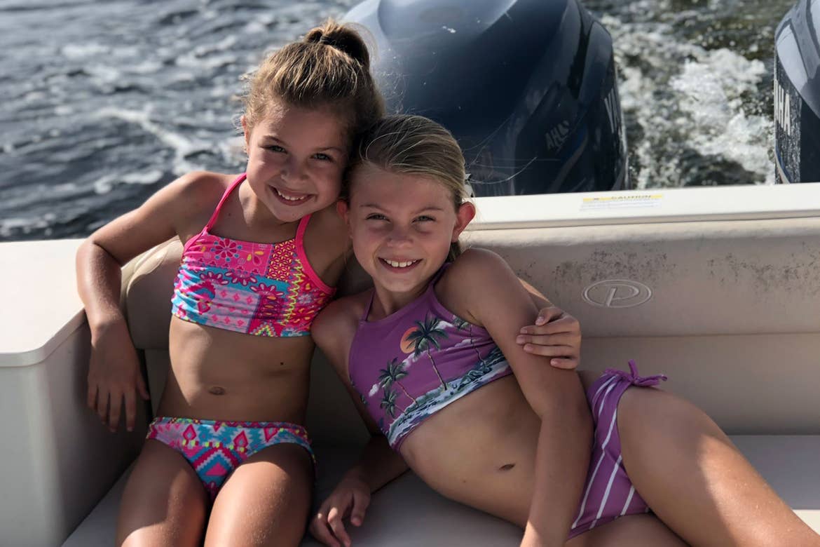 Featured Contributor, Chris Johnston's two daughters, Kyler (left) and Kyndall (right), wear multi-colored swimsuits while riding on a boat in the ocean.