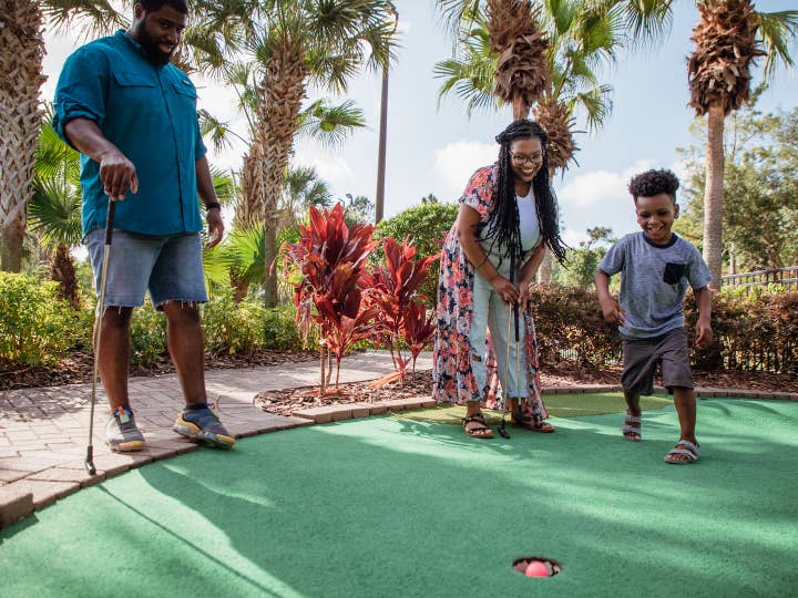 Mother, father and son playing mini golf at Orange Lake Resort near Orlando, Florida.