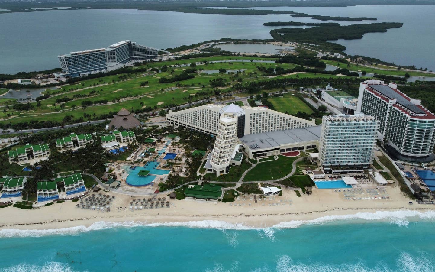 Aerial view of Cancun golf course with oceanfront resorts.