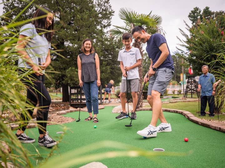 Five guests playing outdoor mini golf at Villages Resort in Flint, Texas.