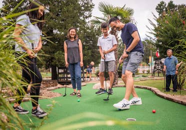 Five guests playing outdoor mini golf at Villages Resort in Flint, Texas.