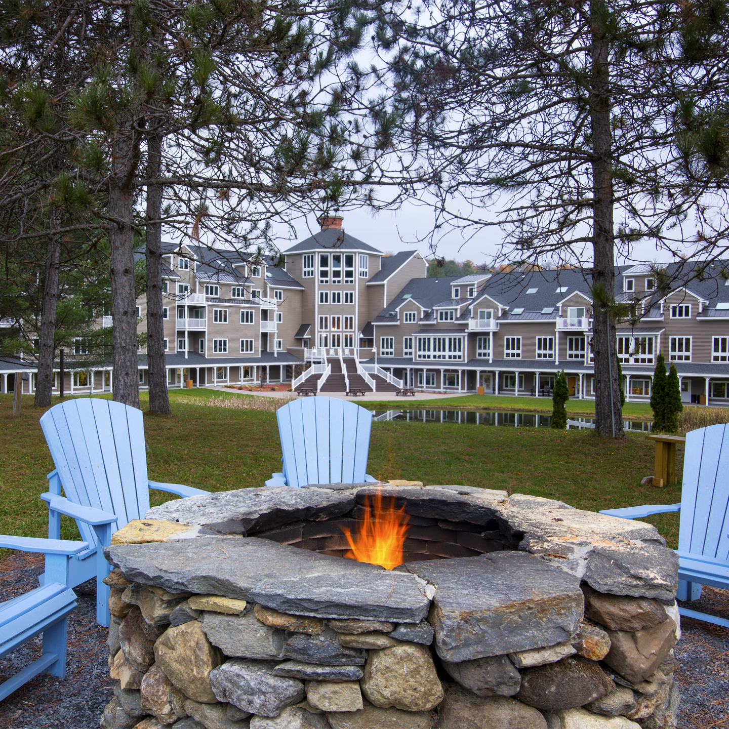 Outdoor fire pit with four blue chairs around it at Mount Ascutney Resort in Brownsville, Vermont.