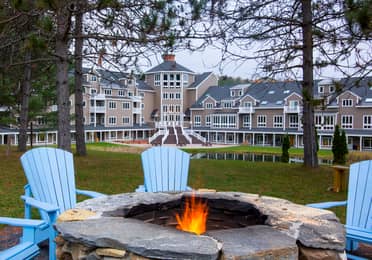 Outdoor fire pit with four blue chairs around it at Mount Ascutney Resort in Brownsville, Vermont.