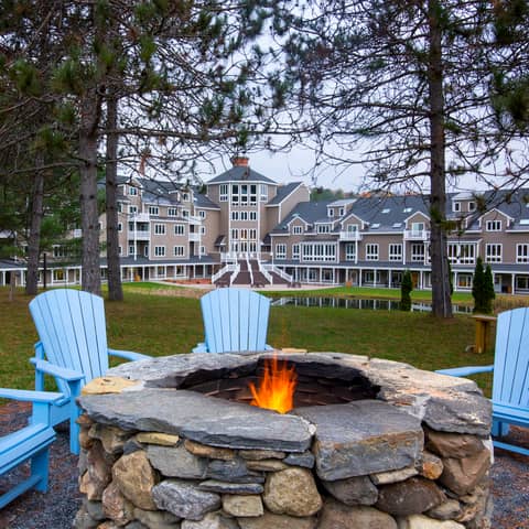 Outdoor fire pit with four blue chairs around it at Mount Ascutney Resort in Brownsville, Vermont.
