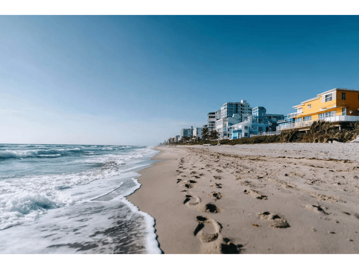 Footprints on sandy beach with ocean waves and buildings in background