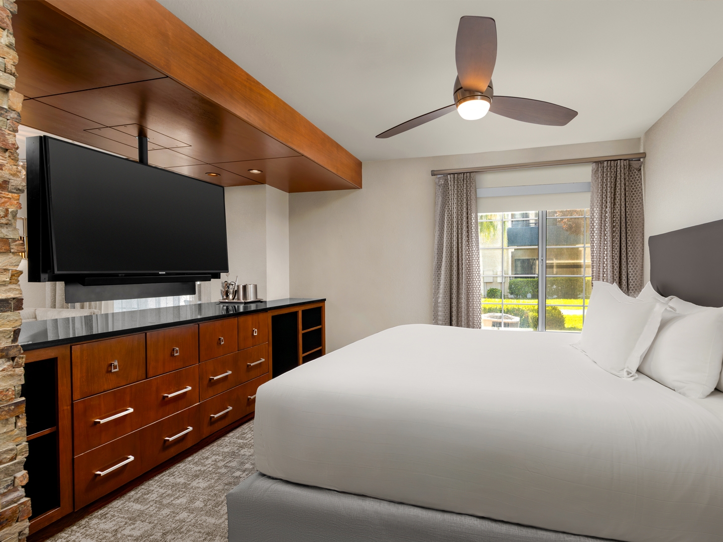 Spacious bedroom with plush bedding and modern in-room entertainment.
