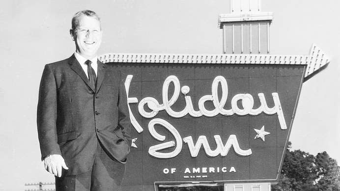 Kemmons Wilson standing in front of a Holiday Inn sign in the early 1970s