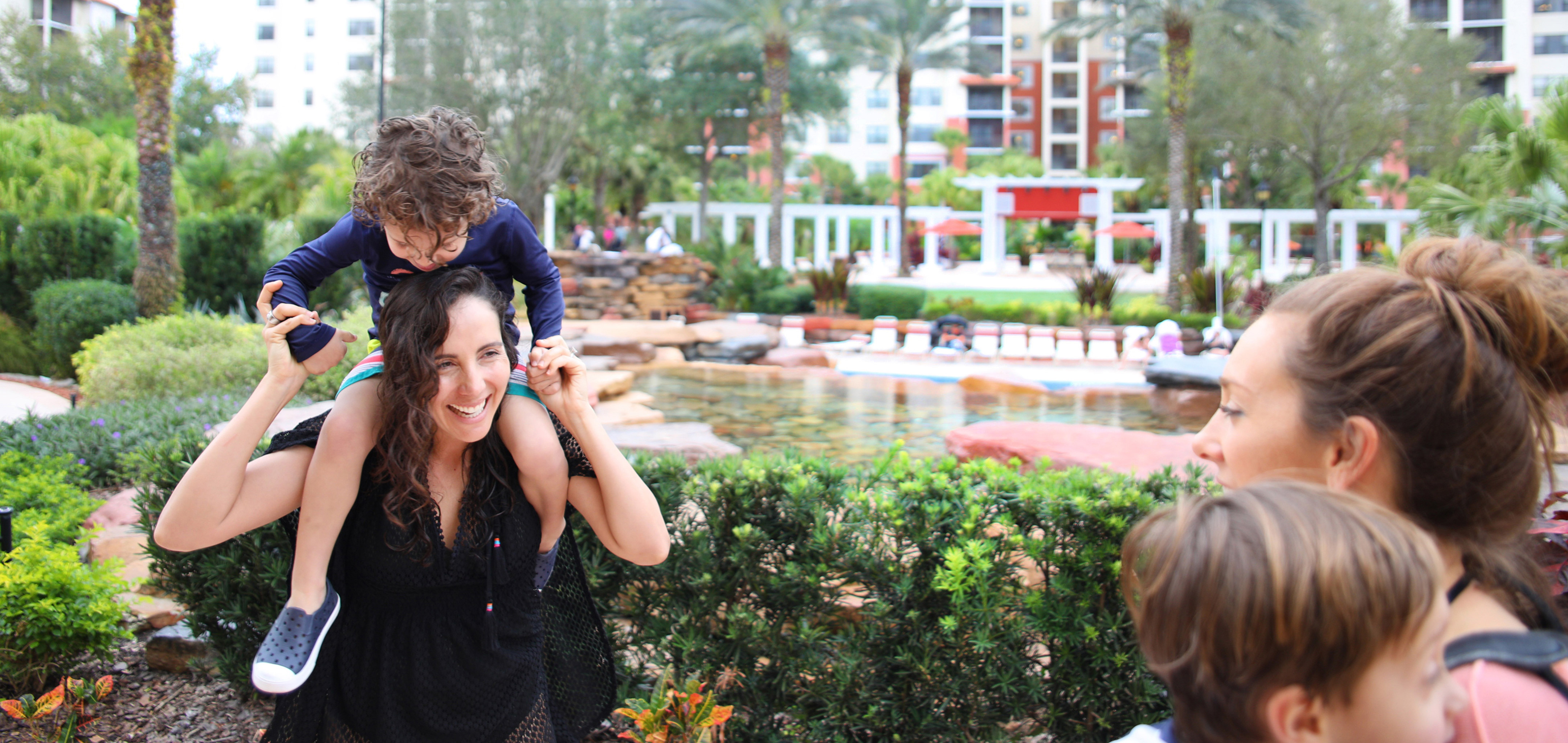 Young child on shoulders of mom exploring River Island at Orange Lake Resort near Orlando, Florida