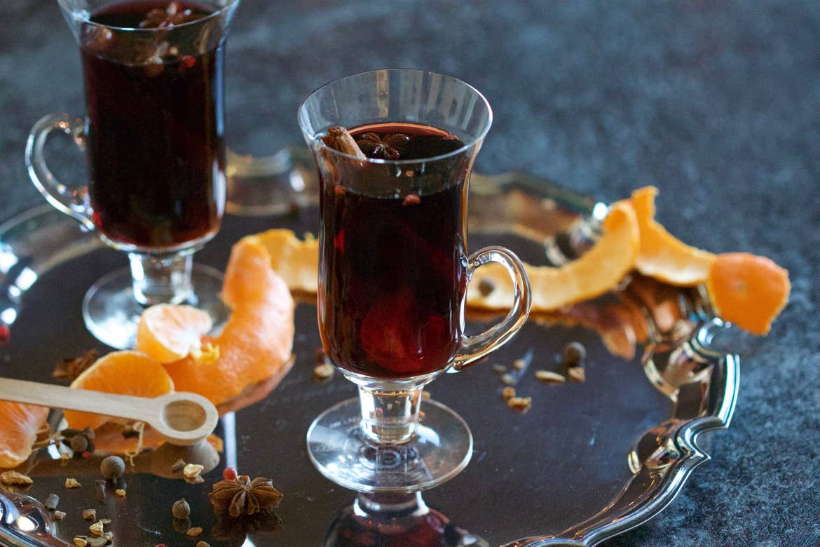 Mulled wine served in a glass mug surrounded by orange peel spirals on top of a silver serving platter.