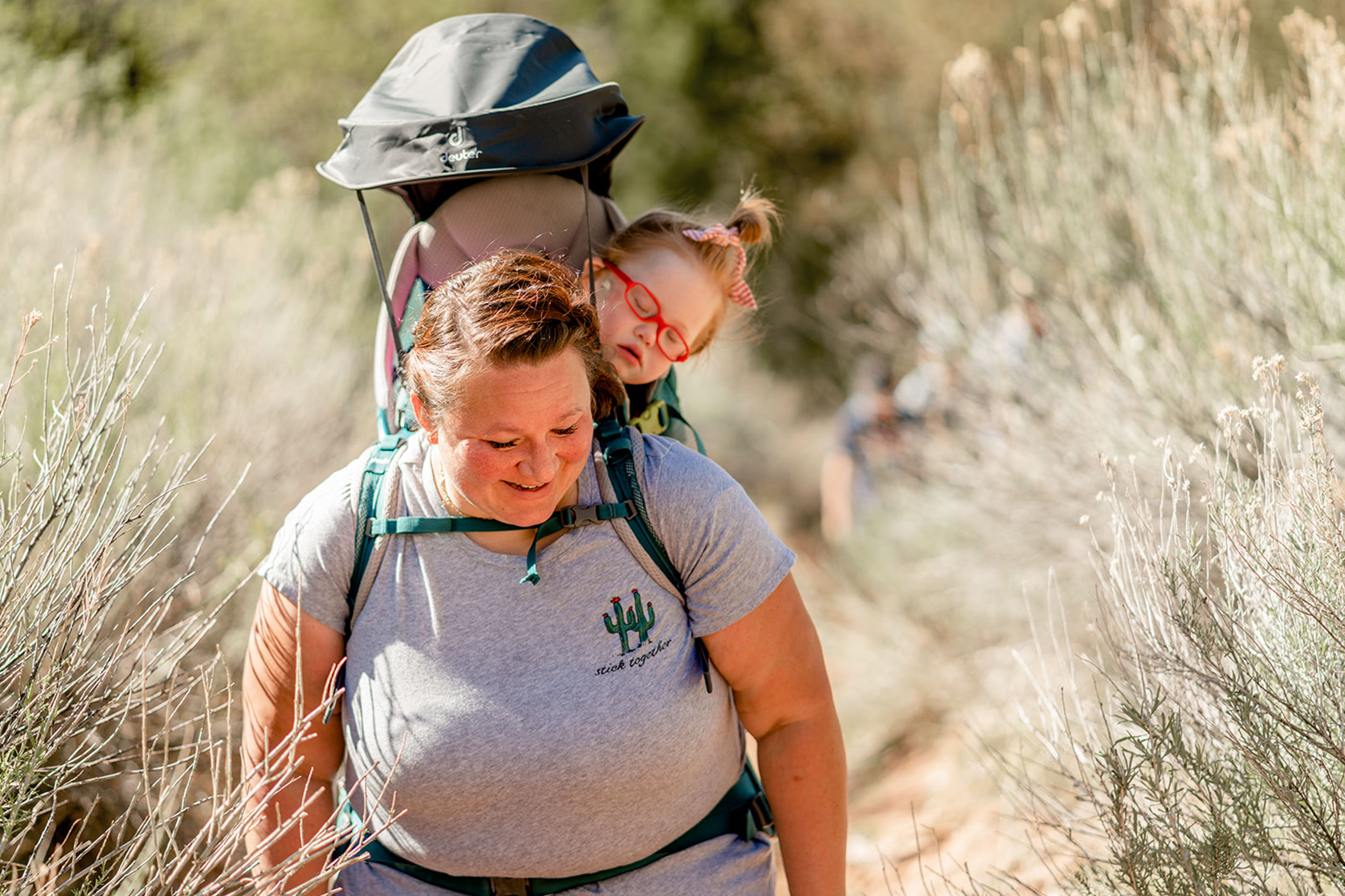 Featured Contributor, Melody Forsyth (left), backpacks with her daughter, Ruby (right), as they walk through some wild plants.