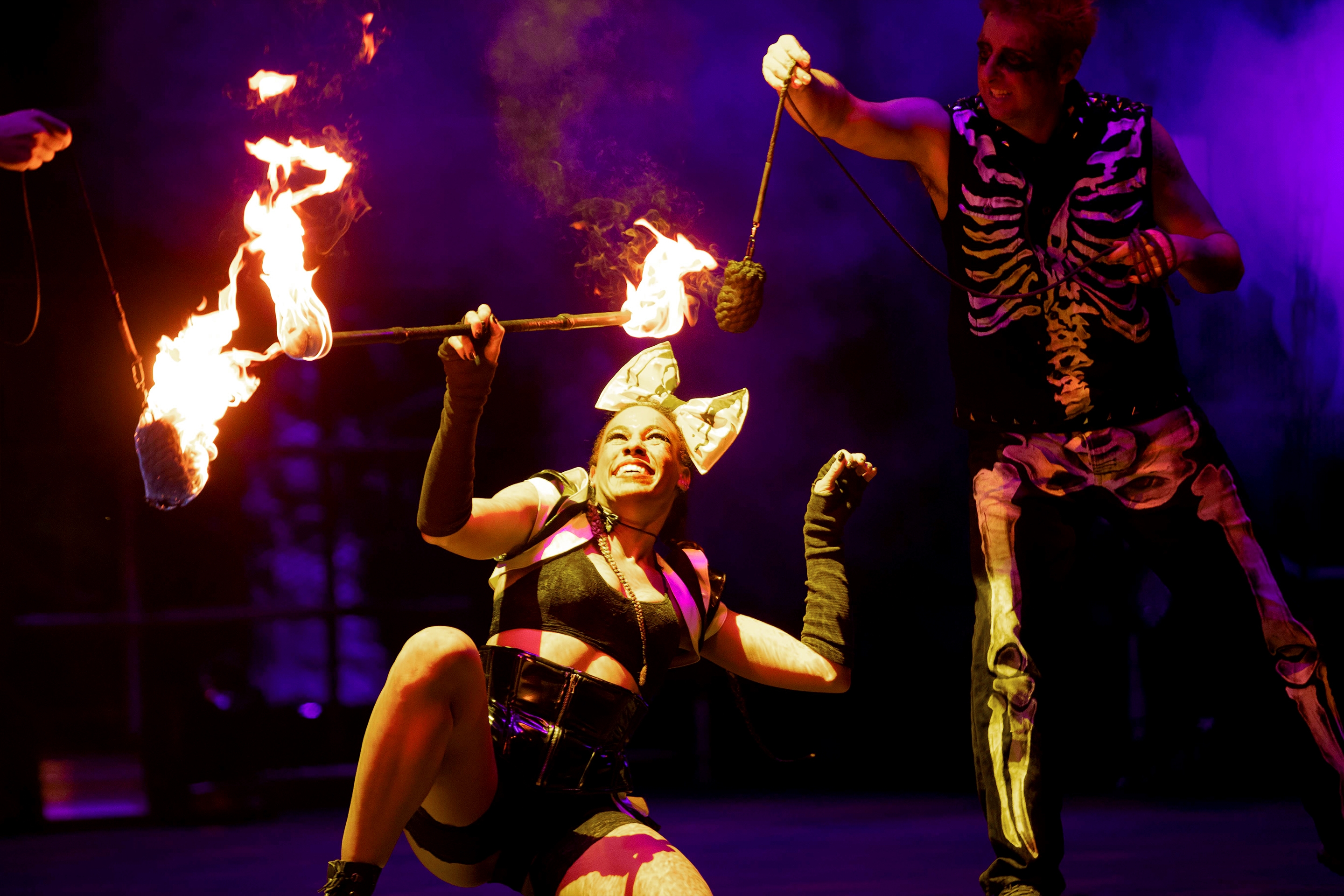 A woman and man perform with fire onstage.