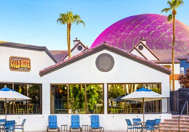 Gold Mine Bar & Grill exterior with Sphere behind and interior seating with a view of the pool at Desert Club Resort in Las Vegas.