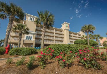 Property building with palm trees  and floral landscaping at Panama City Beach Resort.