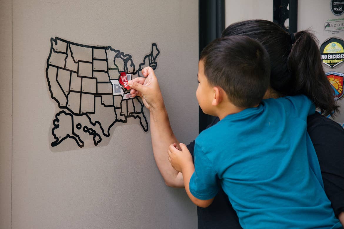 Angelica helps her son place a sticker for Illinois on their RV sticker map to indicate where they traveled.