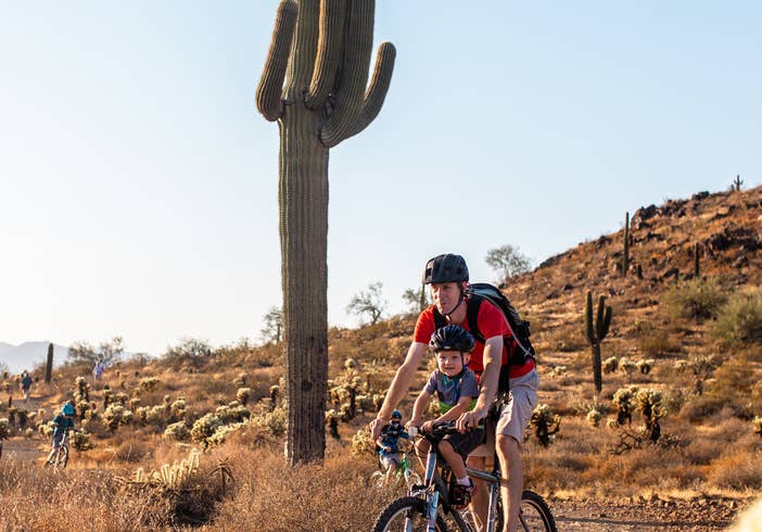 Adult and child riding bike through desert near Scottsdale Resort.