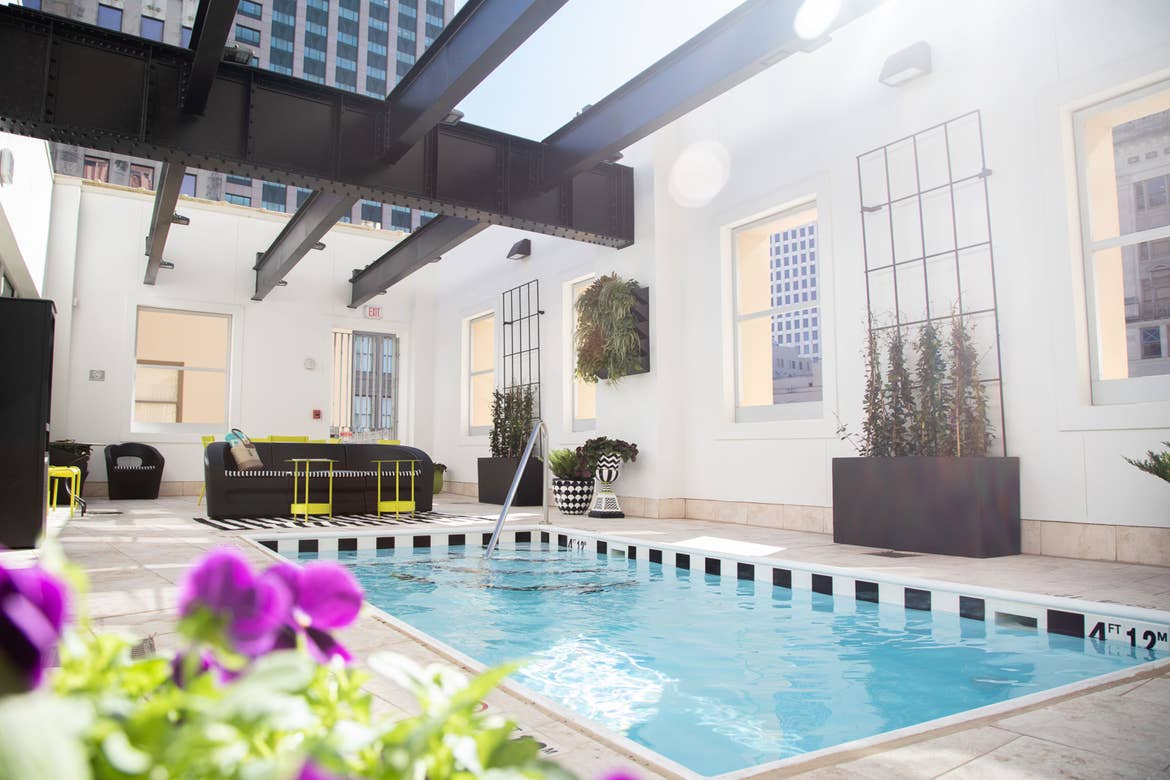 An exposed ceiling, rooftop dipping pool with black and lime green furnishings located in our resort in New Orleans, Louisiana.