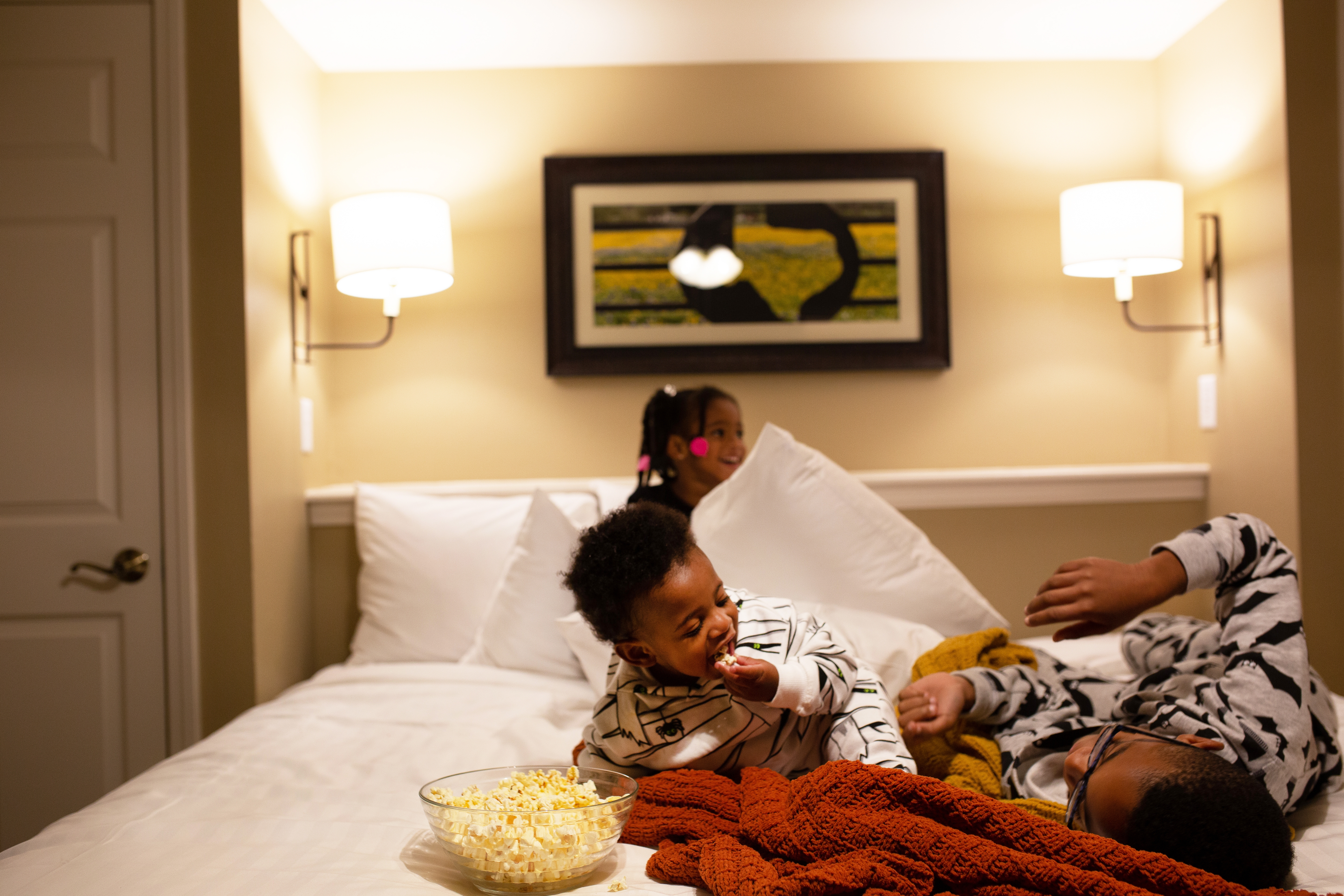 Tina's children laughing on the bed with a bowl of popcorn in their villa at Villages Resort.