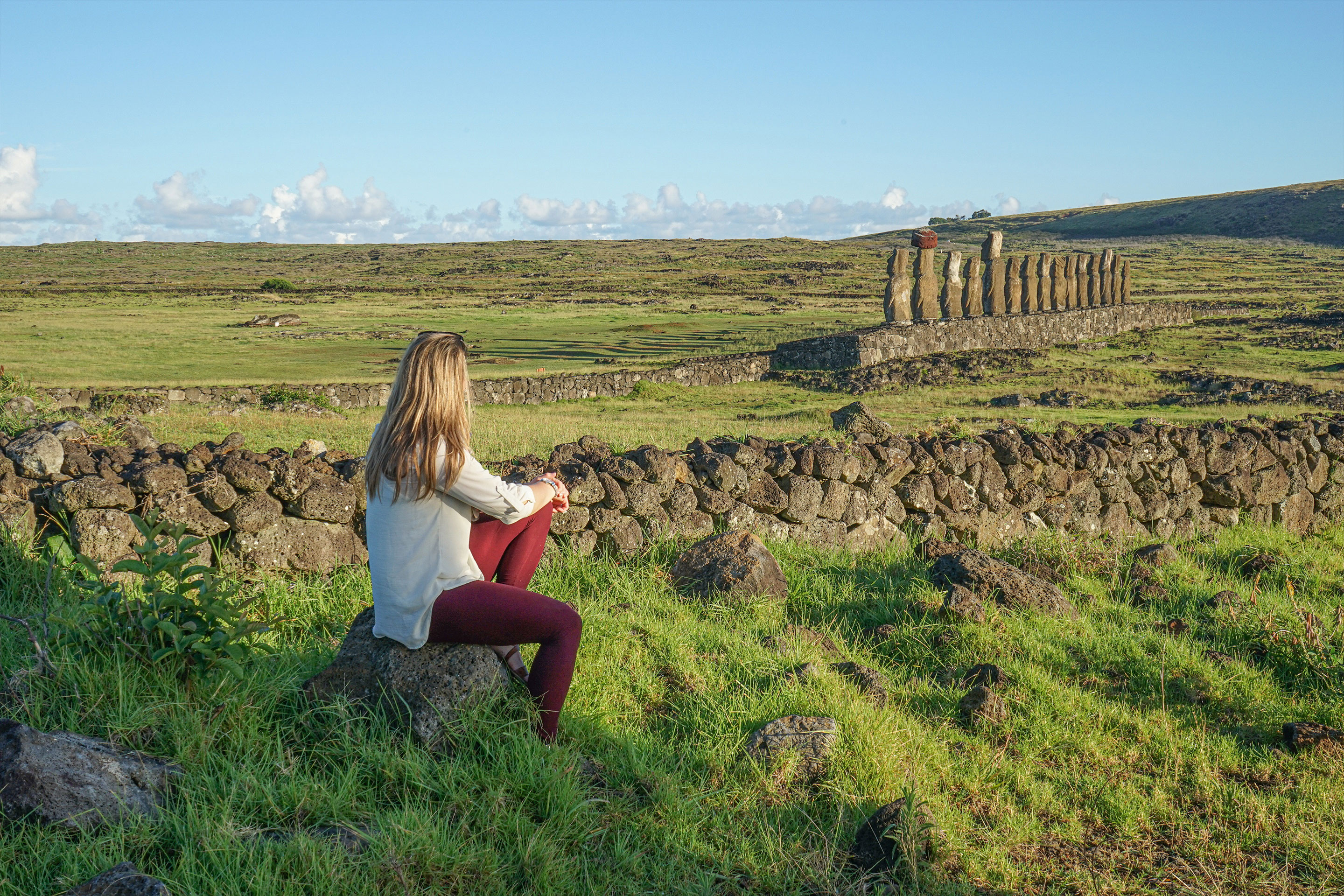 Featured Contributor, Ashlyn George, sits looking at the stone formations of Easter Island.