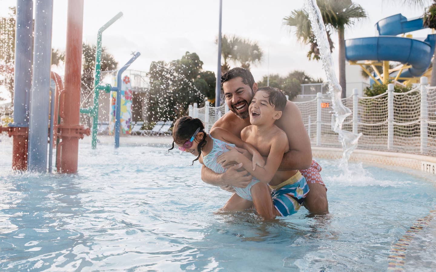 Father and kids playing in a pool.