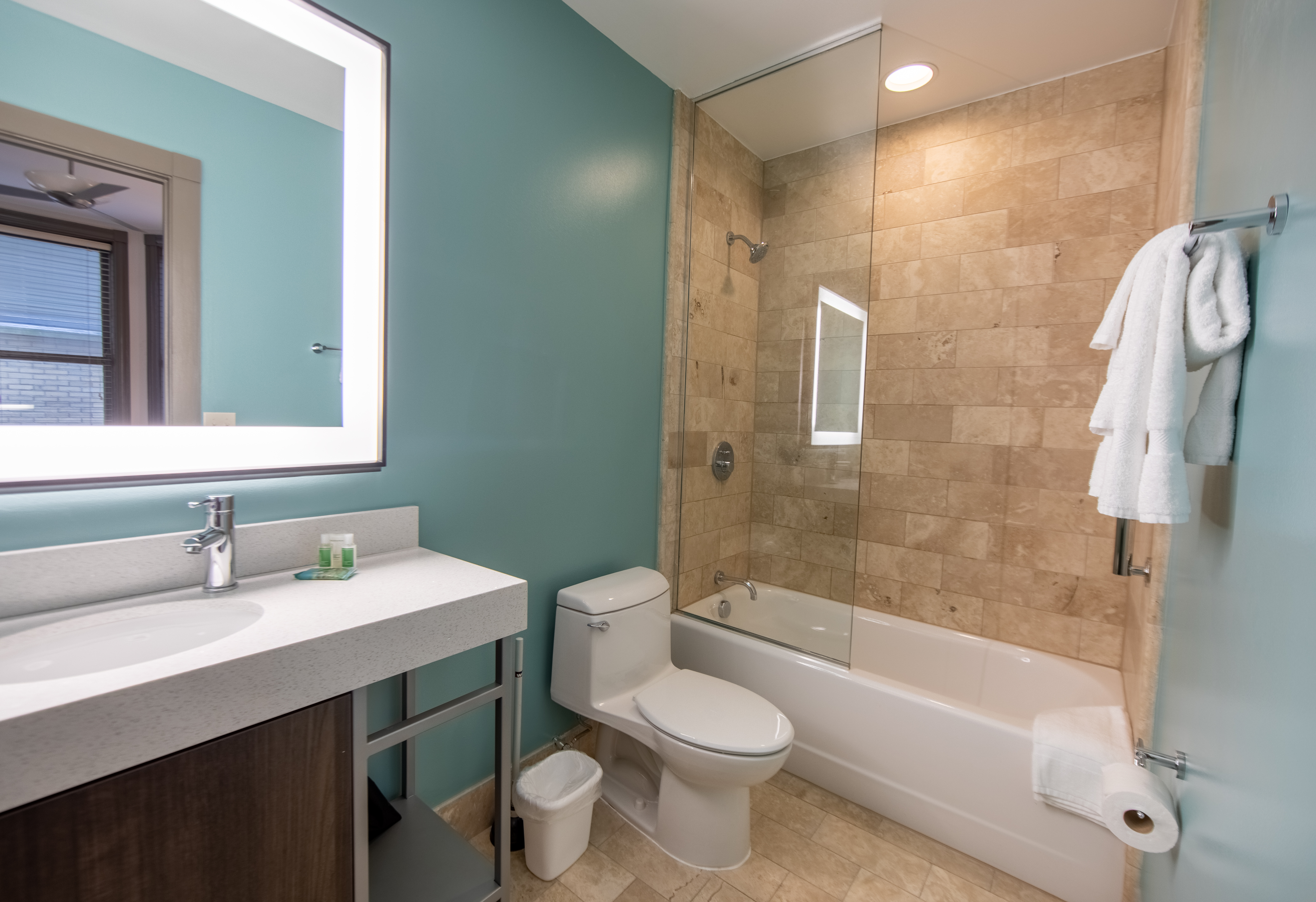 Bathroom in a one bedroom villa with shower/tub combo, toilet and sink with lighted mirror at New Orleans Resort in Louisiana.
