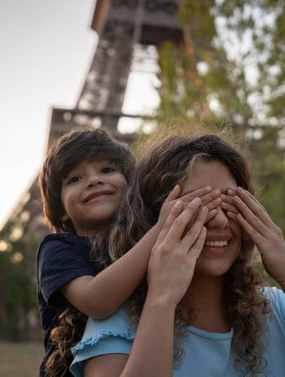 Child cover his mother's eyes in front of the Eiffel Tower in Paris, France