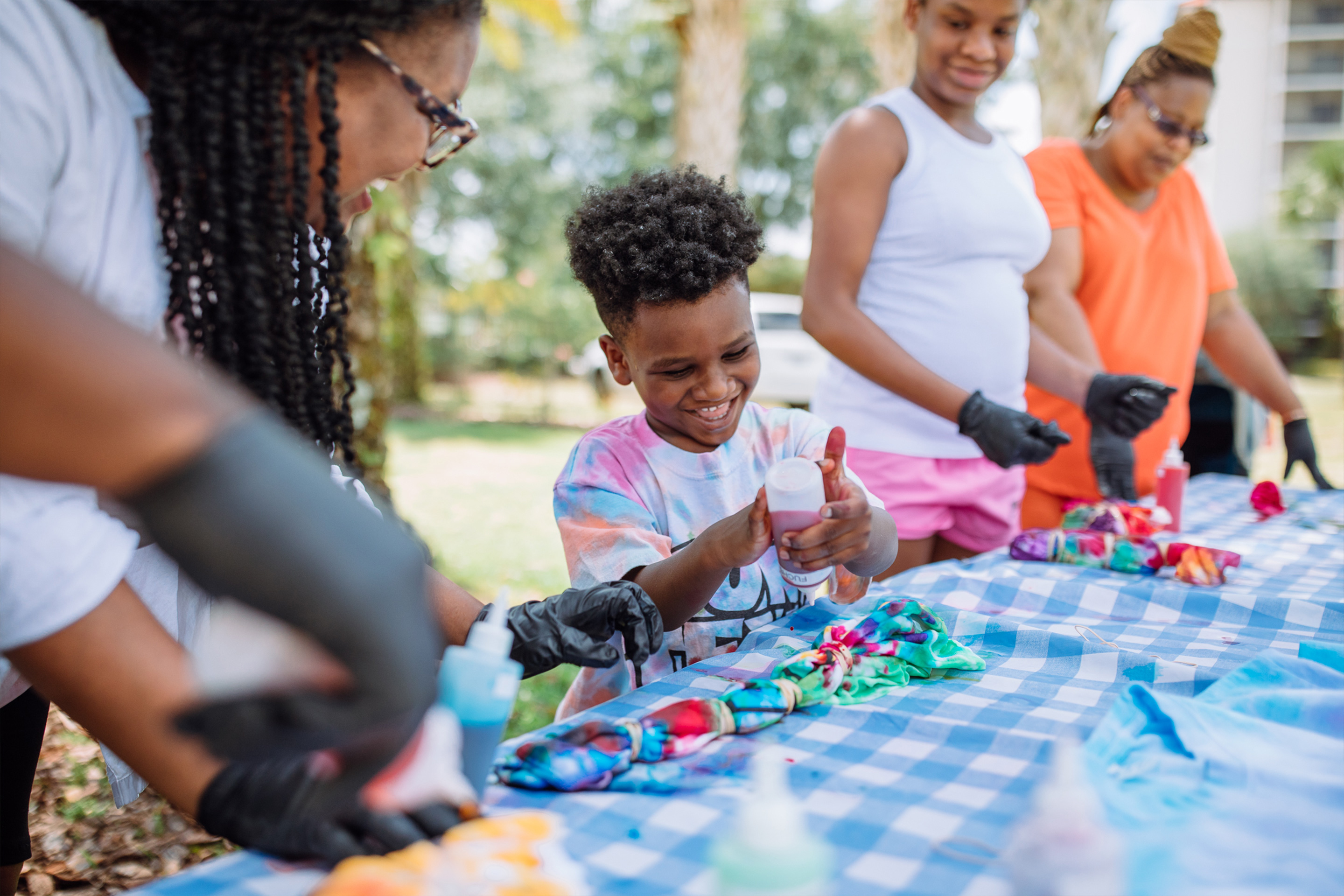 Krystin (left) and Joshua (right) make tie-dye shirts together with our activities team as Sabria and Krystin's Aunt  look from the distance.