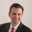 General Manager of the New Orleans Resort, Mike LaRose, wears a black suit, light button up shirt and red necktie.