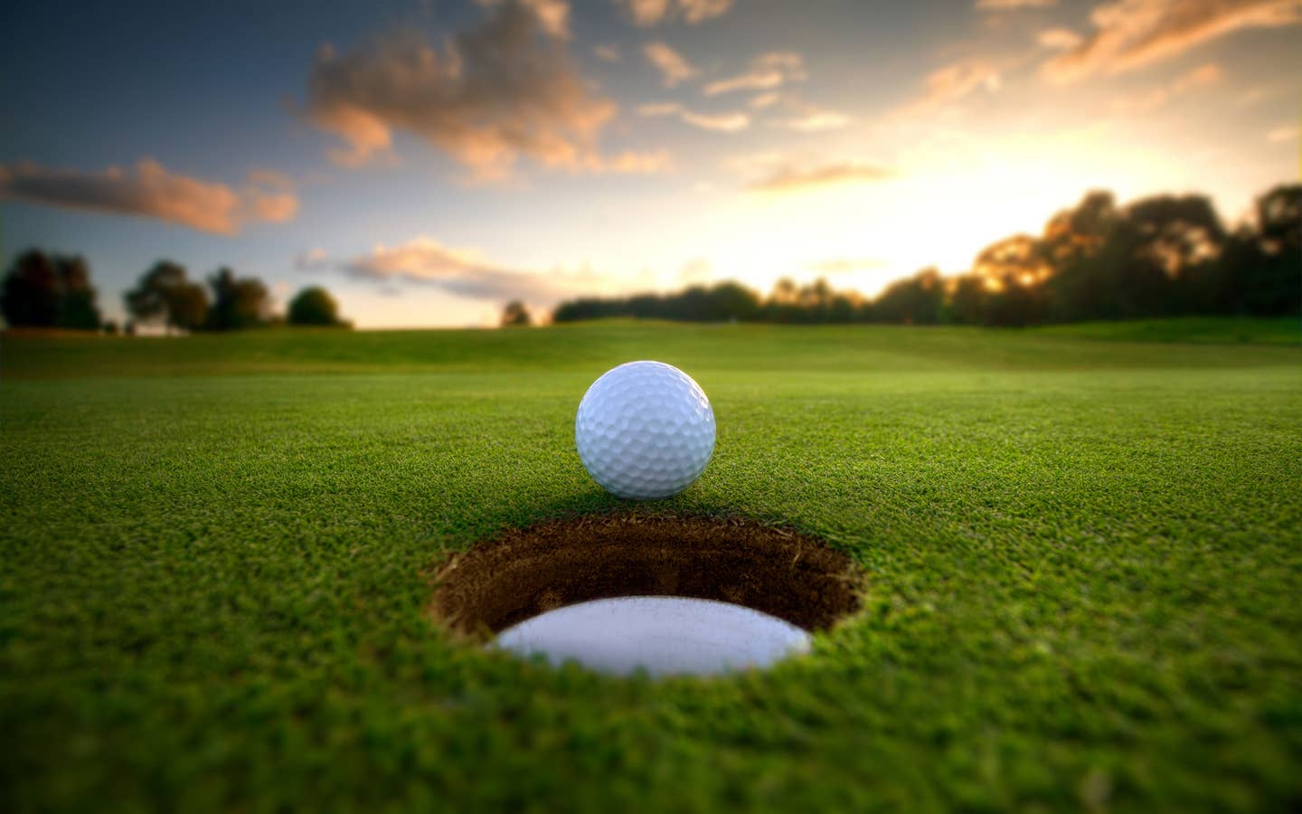 Golf ball close to hole on golf course.