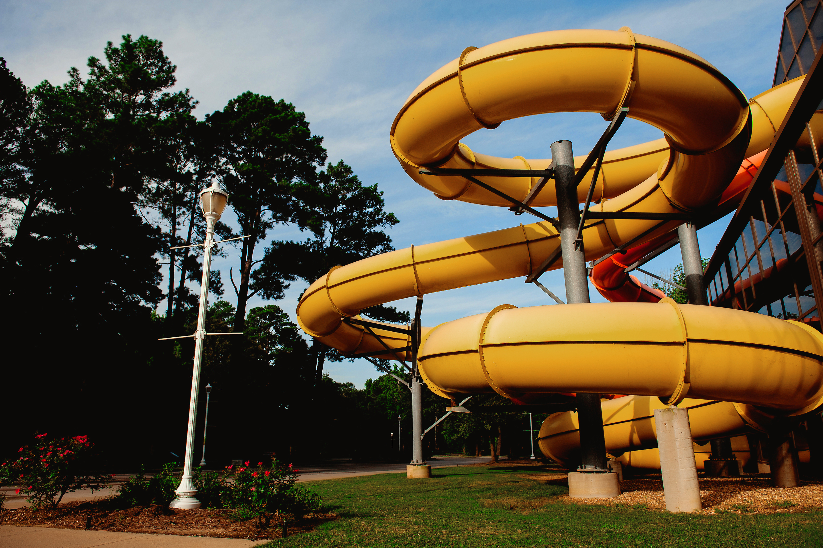 A yellow and orange waterslide protrude from the exterior of an indoor waterpark.