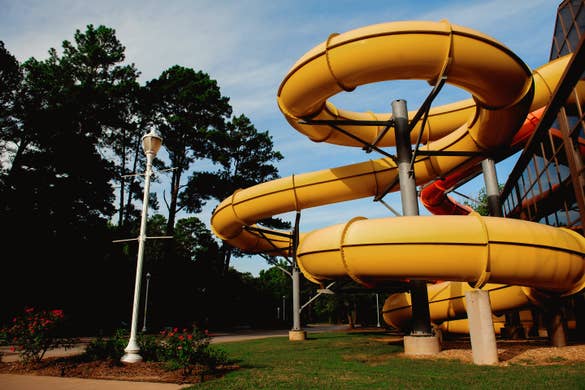 A yellow and orange waterslide protrude from the exterior of an indoor waterpark.