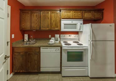 Kitchen with fridge, microwave, oven, dishwasher, and sink in a studio room at Piney Shores Resort in Conroe, Texas