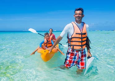 Family doing canoe on the beach at Royal Resorts in Mexico.
