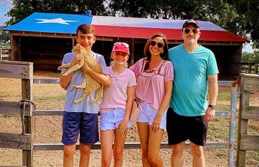 A caucasian family of four stand near a horse stable.
