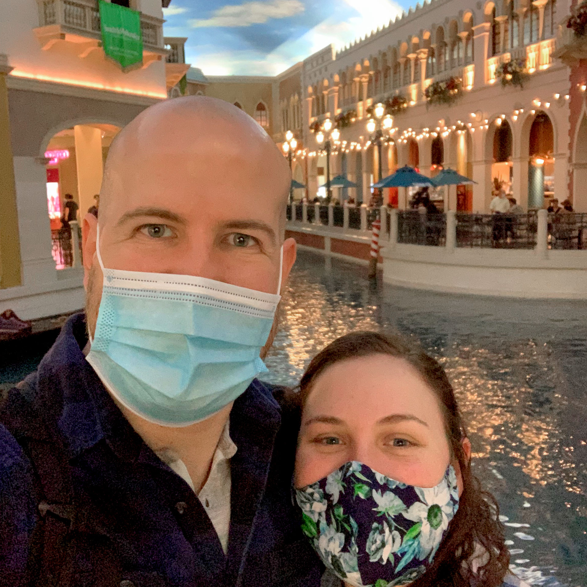 Featured Contributor, Ashley Fraboni (right) and her fiancé, Nicholas (left), wear face masks while posing in front of the canal at the Venetian Las Vegas.
