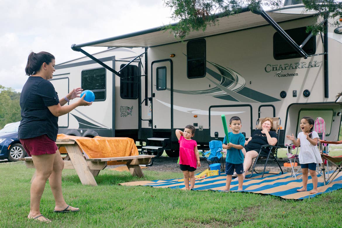 Angelica (left) plays with her three children outside their RV with her mother looking onward behind the children.