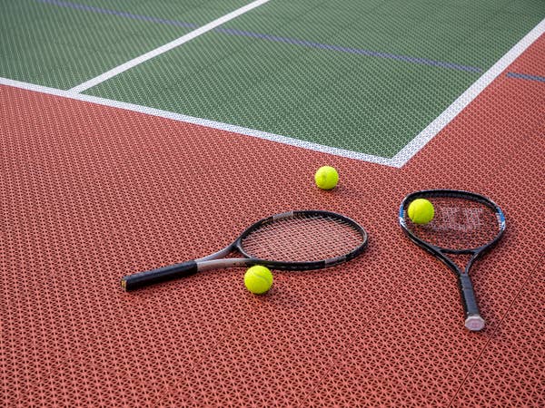 Two tennis rackets and three tennis balls laying on tennis court at Fox River Resort in Sheridan, Illinois.
